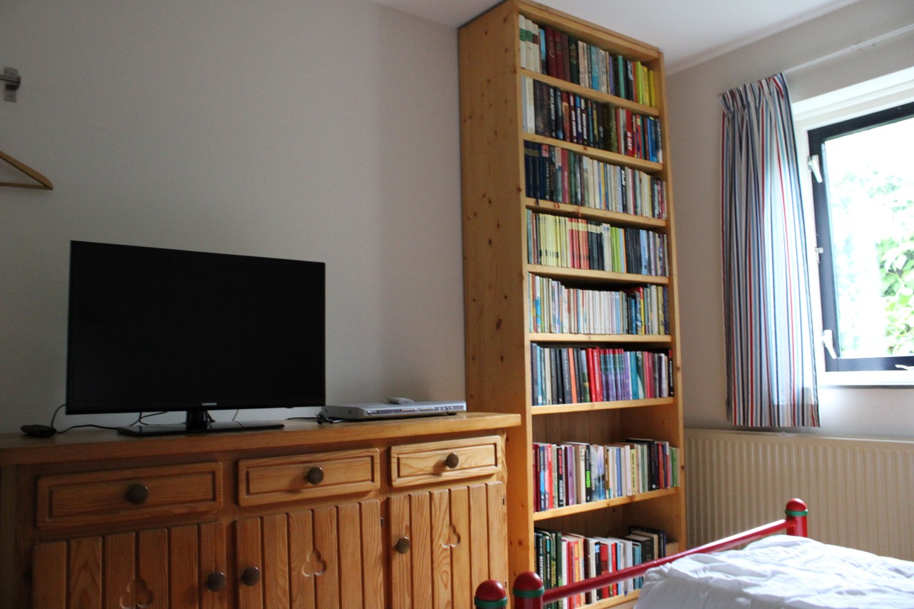 Boekenkast en televisie in slaapkamer met twee 1-persoonsbedden